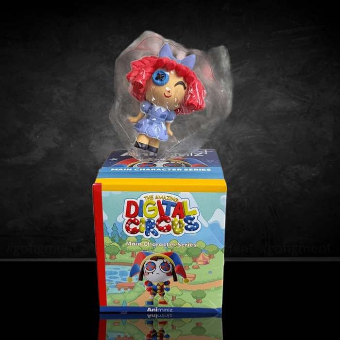 Small Digital Circus figurine with red hair and blue outfit displayed above colorful main character series box on dark background.
