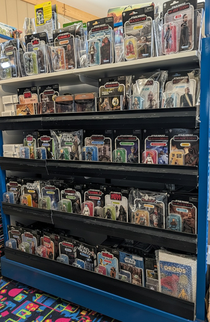 Shelves filled with vintage Star Wars and Indiana Jones action figures in collectible window packaging on black display racks
