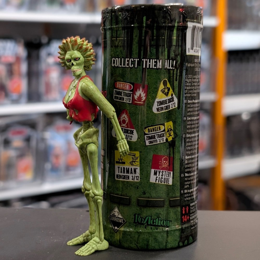 Super7 neon green female zombie figure with torn red top posed beside Return of the Living Dead collectible blind box