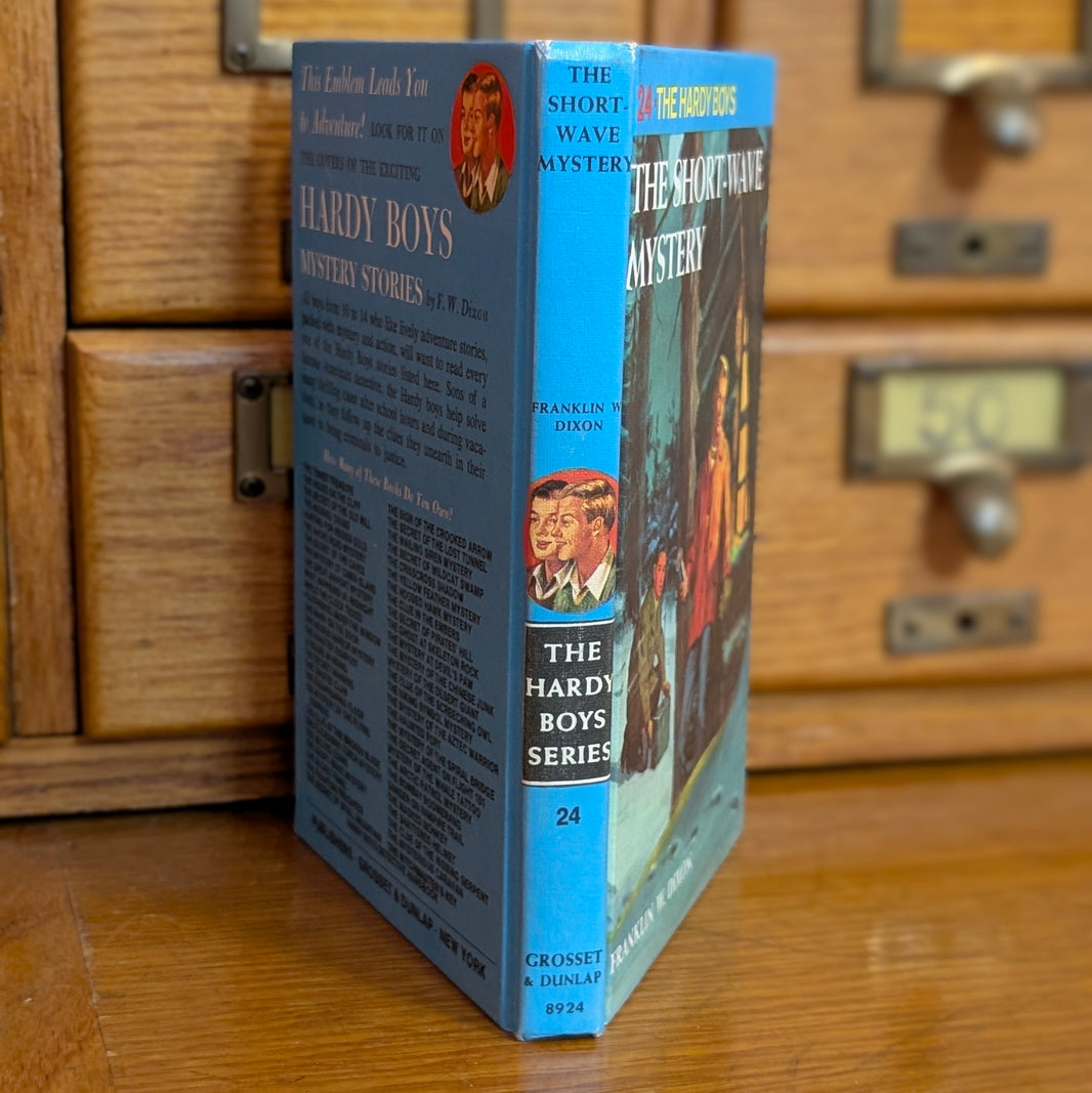 Vintage Hardy Boys book The Short Wave Mystery by Grosset & Dunlap Inc standing on wooden surface