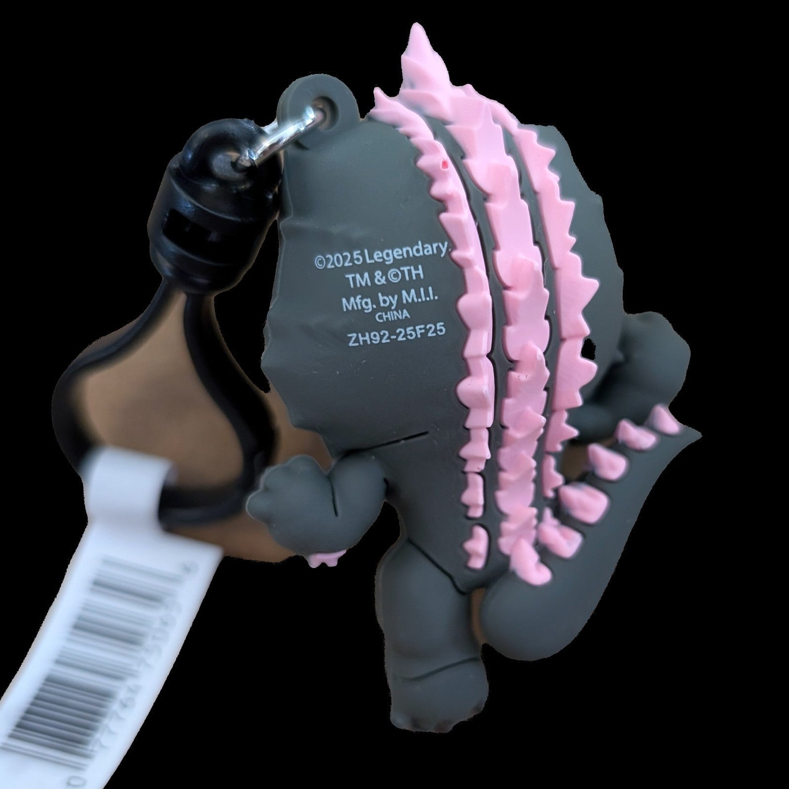 Back view of Monogram Evolved Godzilla 3D foam bag clip keychain with pink dorsal plates and attached metal ring.