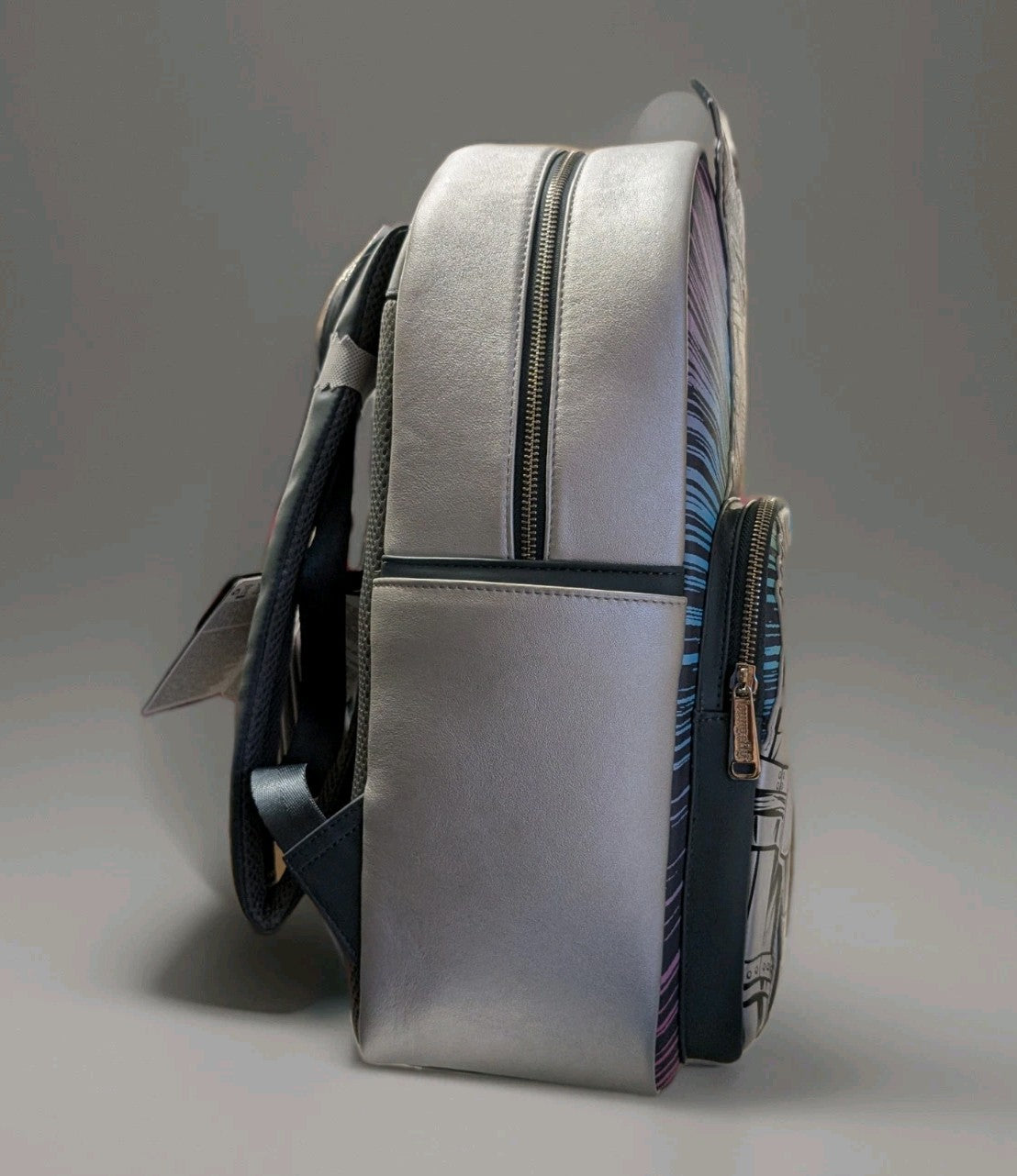 Side profile of Loungefly full-size backpack in metallic silver with zipped compartments and black adjustable straps visible