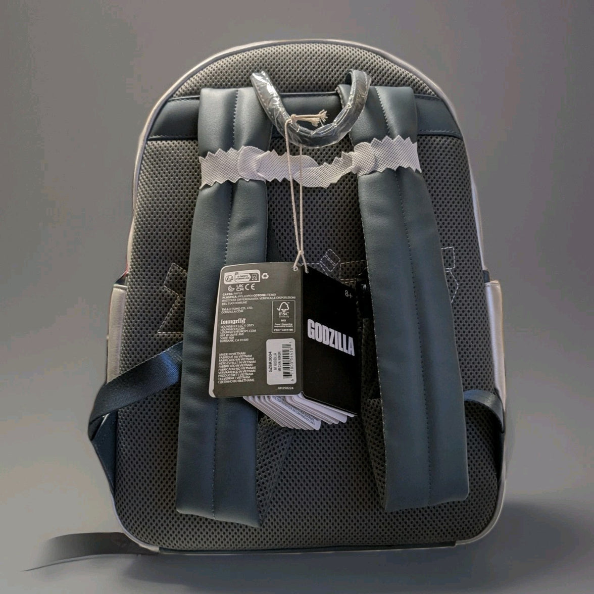 Back view of Loungefly Godzilla Mechagodzilla full-size backpack with padded straps and attached product tags visible