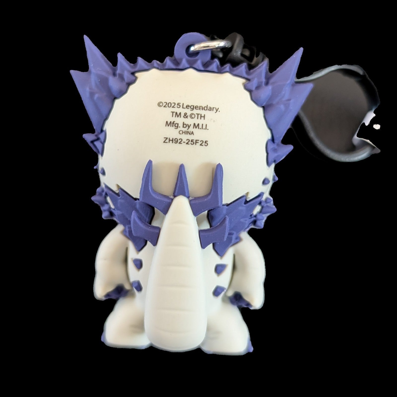 Back view of a purple and white Monogram Godzilla-Kong New Empire 3D foam bag clip keychain with details on the tag