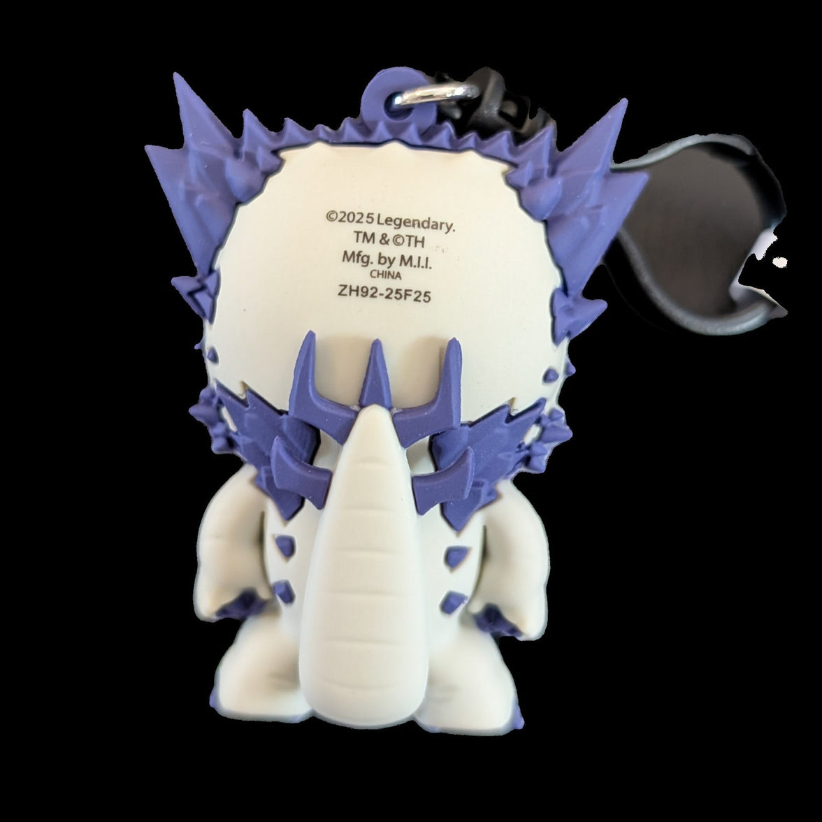 Back view of a purple and white Monogram Godzilla-Kong New Empire 3D foam bag clip keychain with details on the tag