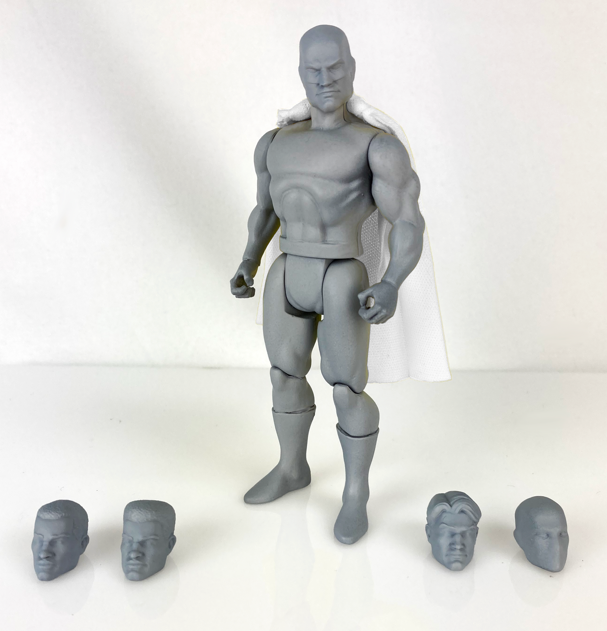 Boss Fight Studio Llc 5-inch gray blank retro-style hero figure with muscular build and five interchangeable heads on white surface