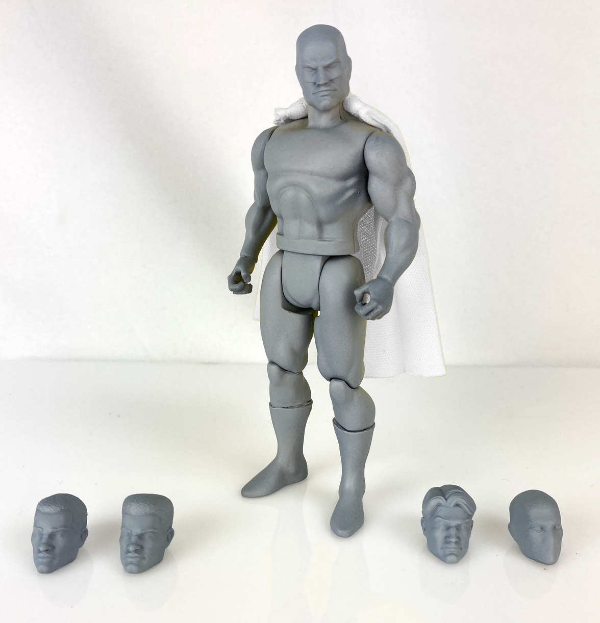 Boss Fight Studio Llc 5-inch gray blank retro-style hero figure with muscular build and five interchangeable heads on white surface