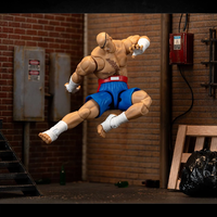 Jada Toys Ultra Street Fighter II Sagat 6-inch action figure in blue shorts mid-air pose against urban backdrop
