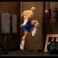 Jada Toys Ultra Street Fighter II Sagat 6-inch action figure posed mid-kick in urban alley with brick walls and debris