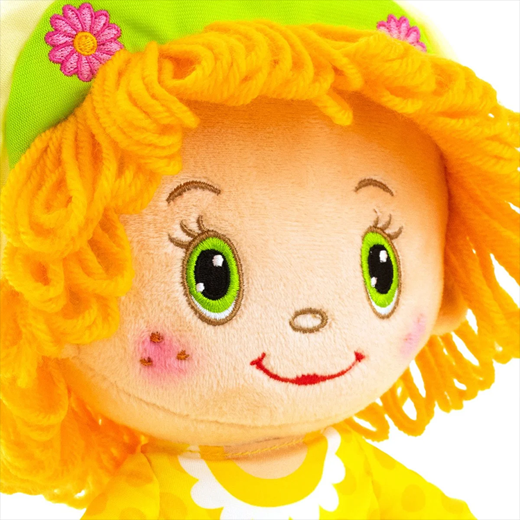 Close-up of Loyal Subjects Strawberry Shortcake Lemon Meringue 14-inch scented rag doll with bright green eyes and yellow yarn hair