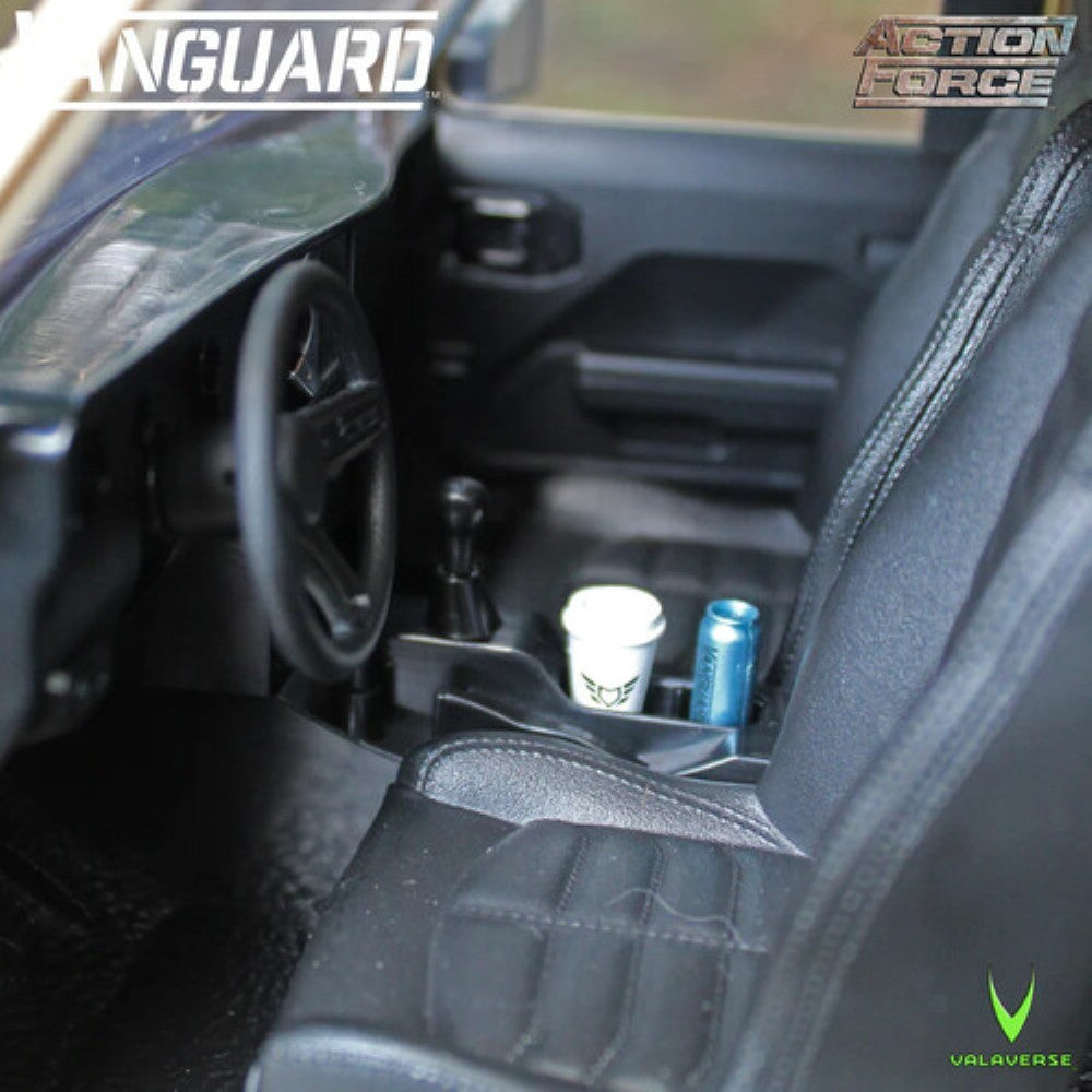 Miniature vehicle interior with steering wheel, gear shift, black seats, a cup, and a blue can