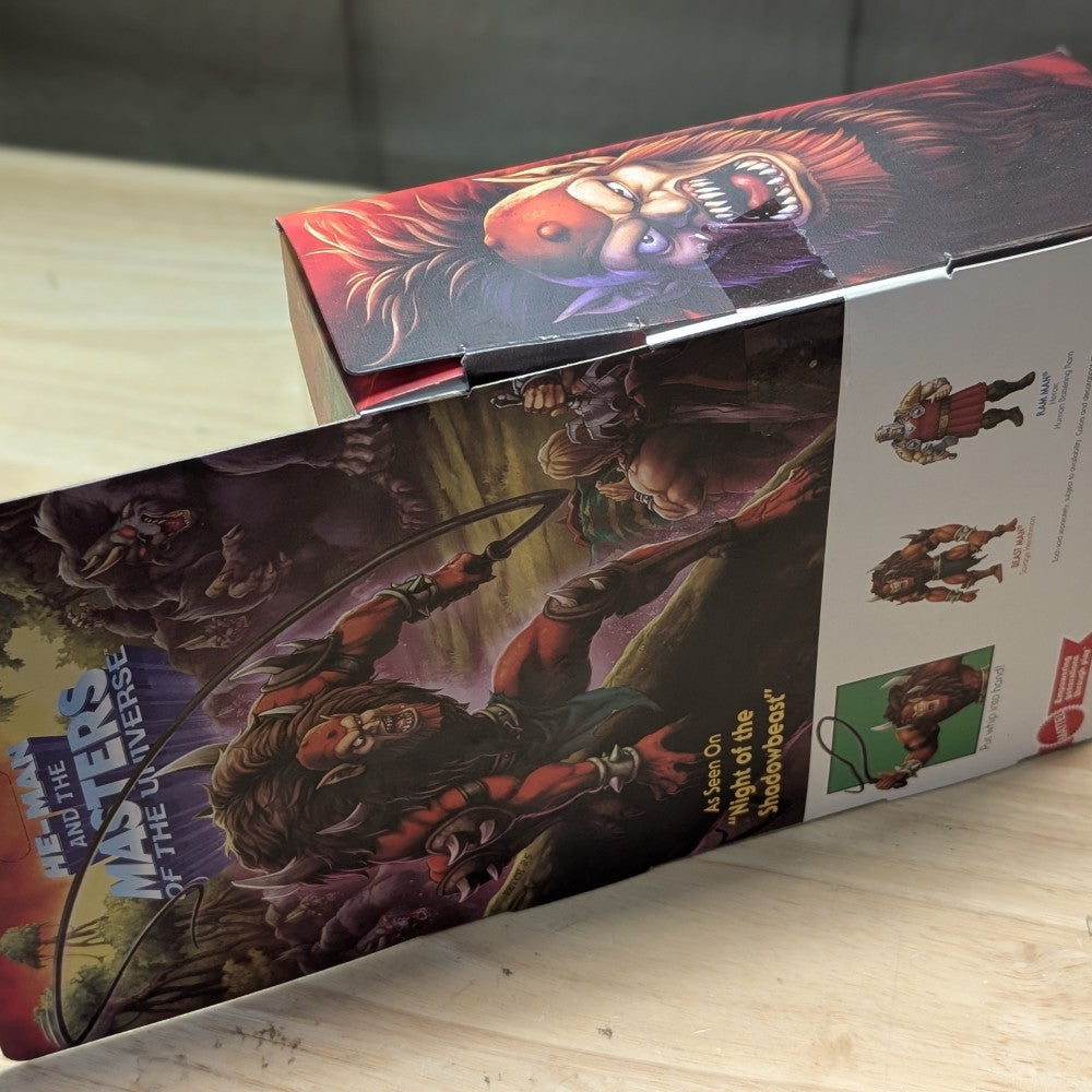 Mattel Beast-Man Masters of the Universe Origins Deluxe action figure packaging with character artwork and product details on wooden surface