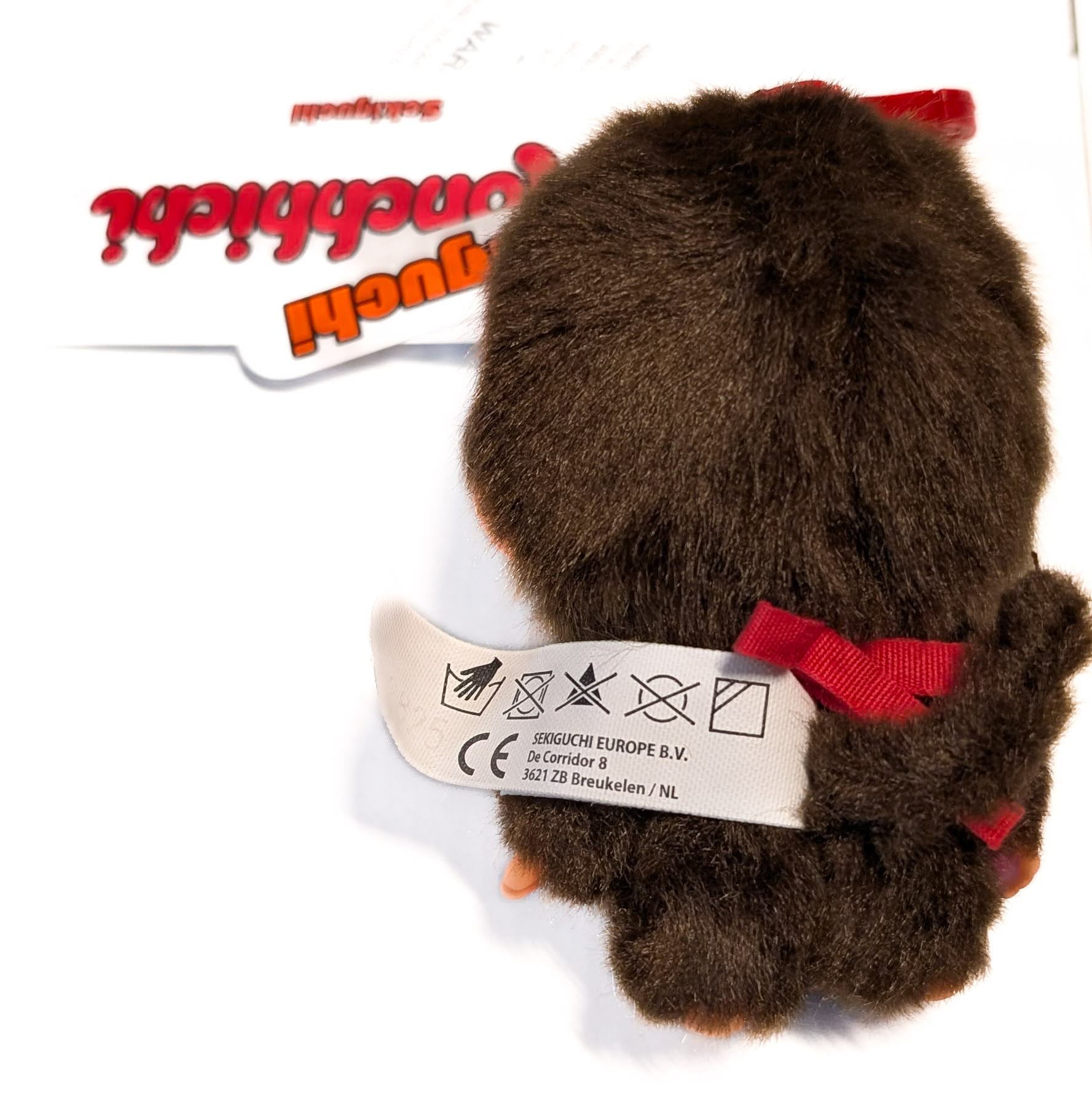 Sekiguchi Monchhichi Boy Classic Big Head plush mascot clip with red bow and attached product tag visible
