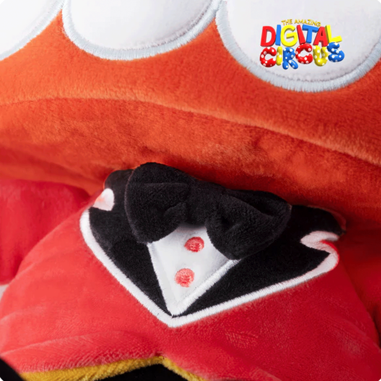 Close-up of Glitch Caine plush wearing black bowtie, red jacket with white shirt detail from The Amazing Digital Circus