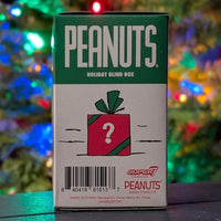 Super7 Peanuts Holiday Blind Box packaging with red present and question mark against festive colorful lights background