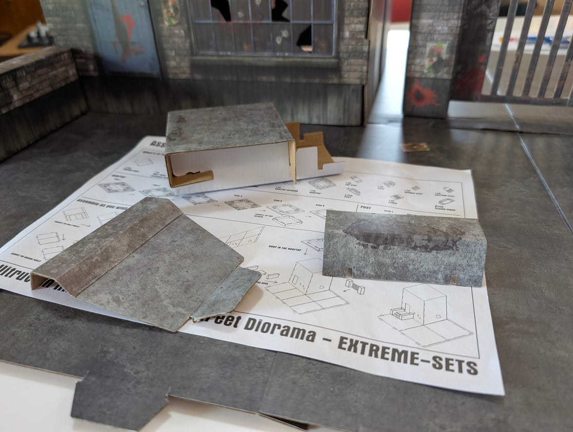 Parts of Vitruvian H.A.C.K.S. Series Z Zombie Diorama 1/18 Scale Street by Boss Fight Studio Llc laid out on assembly instructions