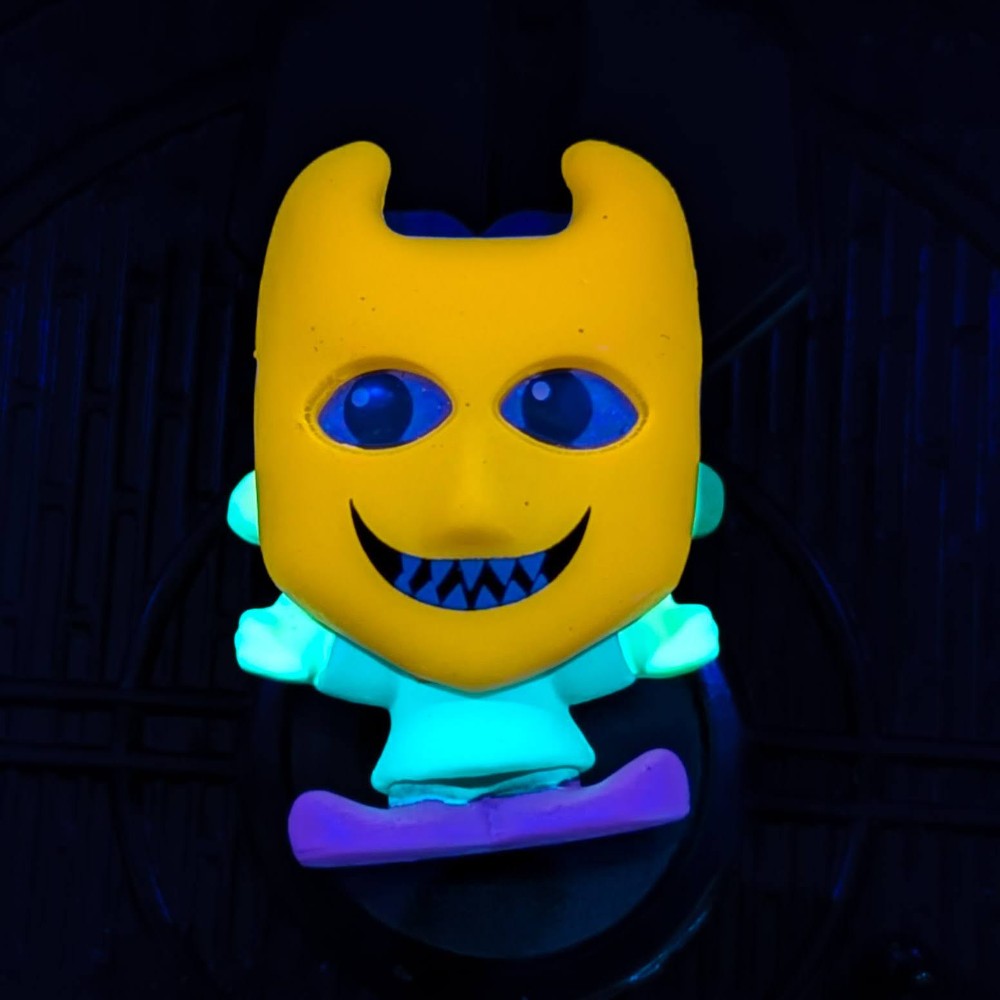Go Figment black light Disney Doorables mini-figure with yellow mask and glowing teal body on purple base under dark light