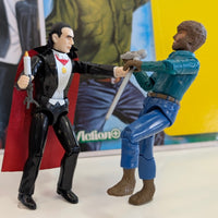 Universal Monsters Dracula ReAction figure in black suit with red cape facing Wolfman figure in blue shirt on white surface