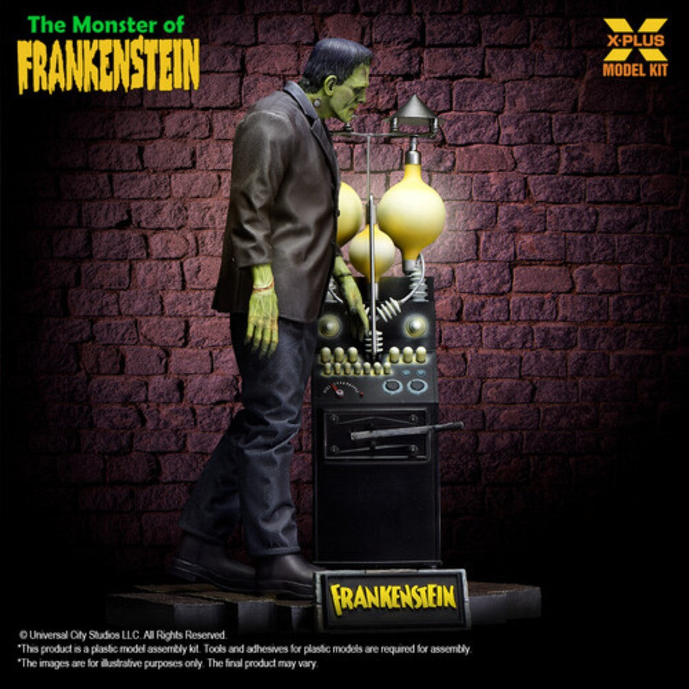 A model kit figure of Frankenstein's monster standing beside a vintage scientific machine against a brick wall background