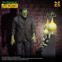 Green-skinned Frankenstein figure posed by a vintage-style electrical lab setup against a brick wall background
