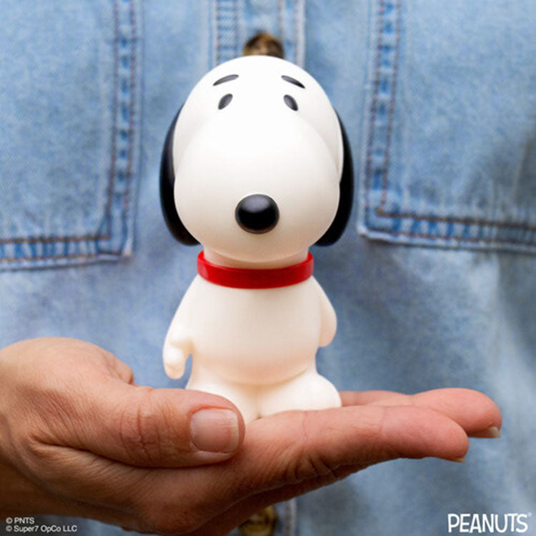 Funko Peanuts Snoopy walking vinyl figure standing on hand with red collar and blue denim background