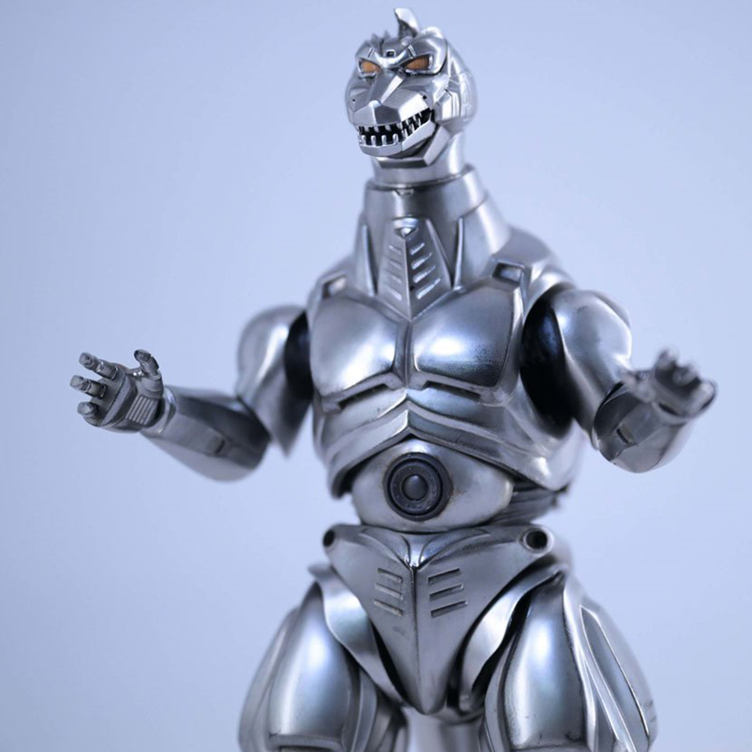 Silver mechanical robot dinosaur figure with articulated limbs and detailed armor against soft blue background