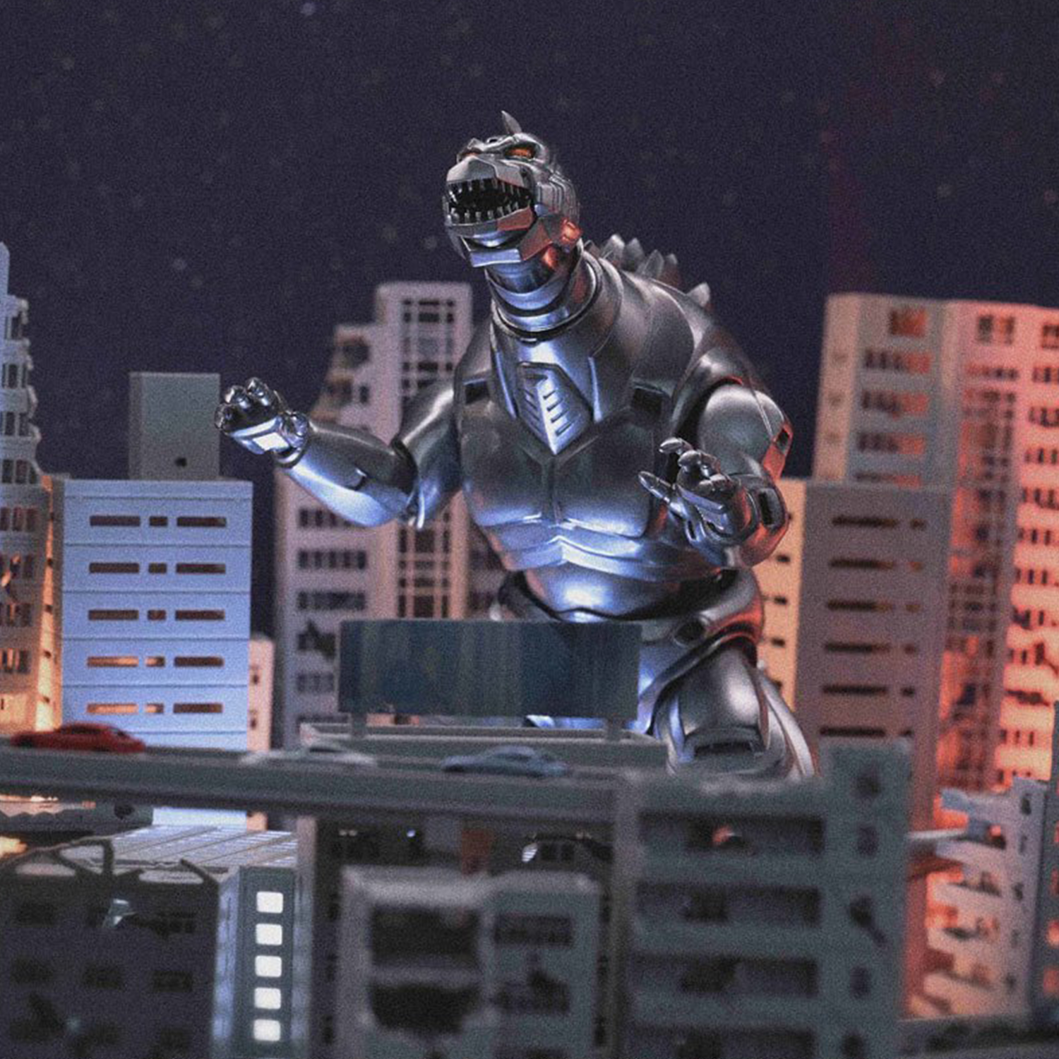 Silver robot dinosaur with glowing orange eyes towering over a detailed miniature cityscape at night.