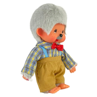 Vintage Monchhichi doll with gray hair, plaid shirt, red bow tie, and brown shorts against white background