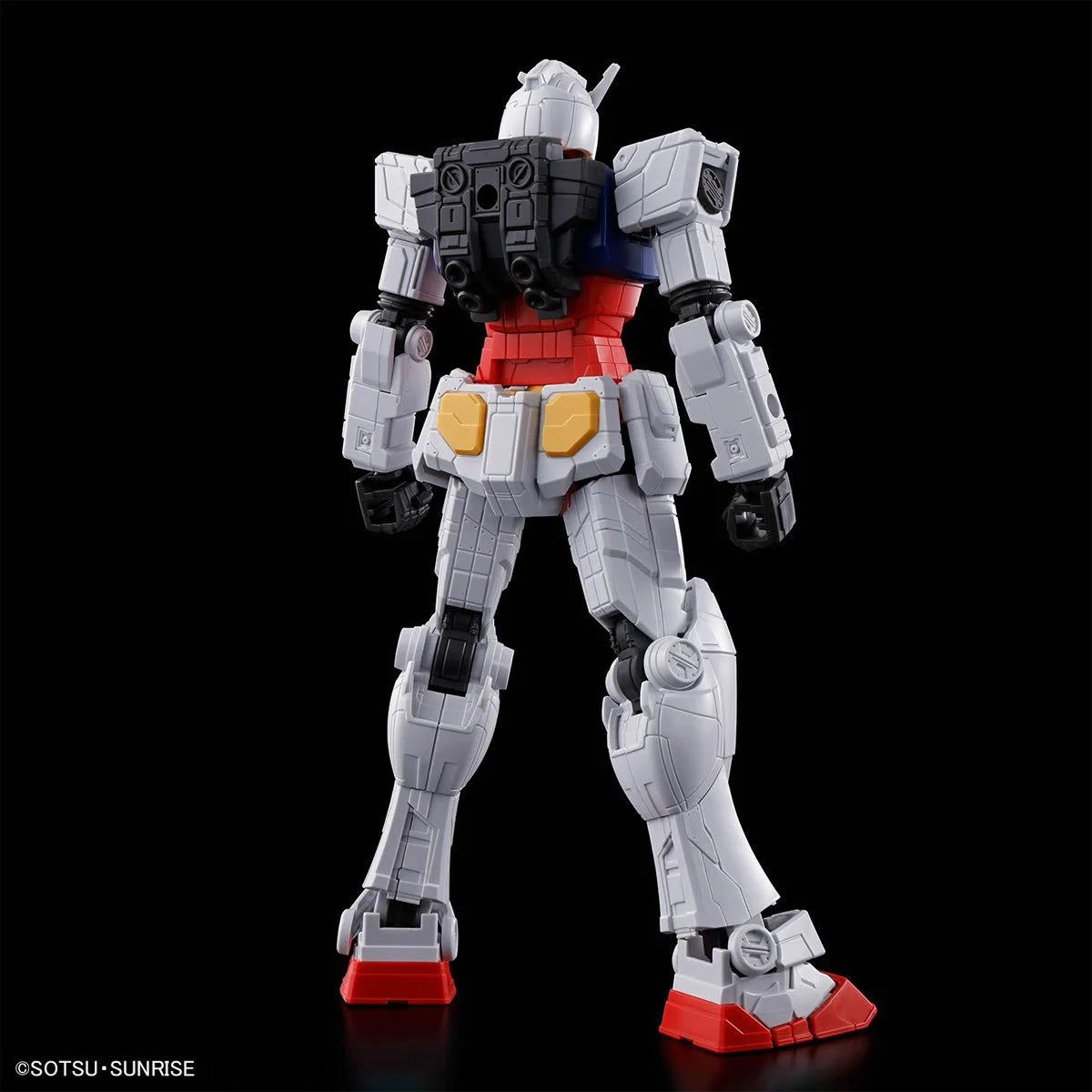 Rear view of articulated white and red Gundam figure with mechanical backpack and detailed panel lines on black background