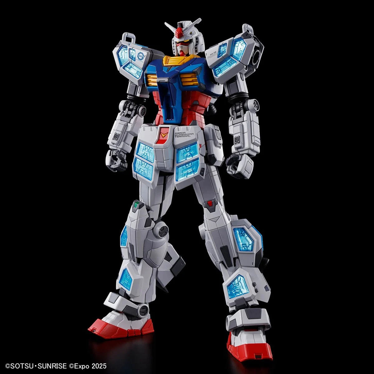 Standing Gundam model in white, red, and blue with detailed translucent blue panel accents on a black background
