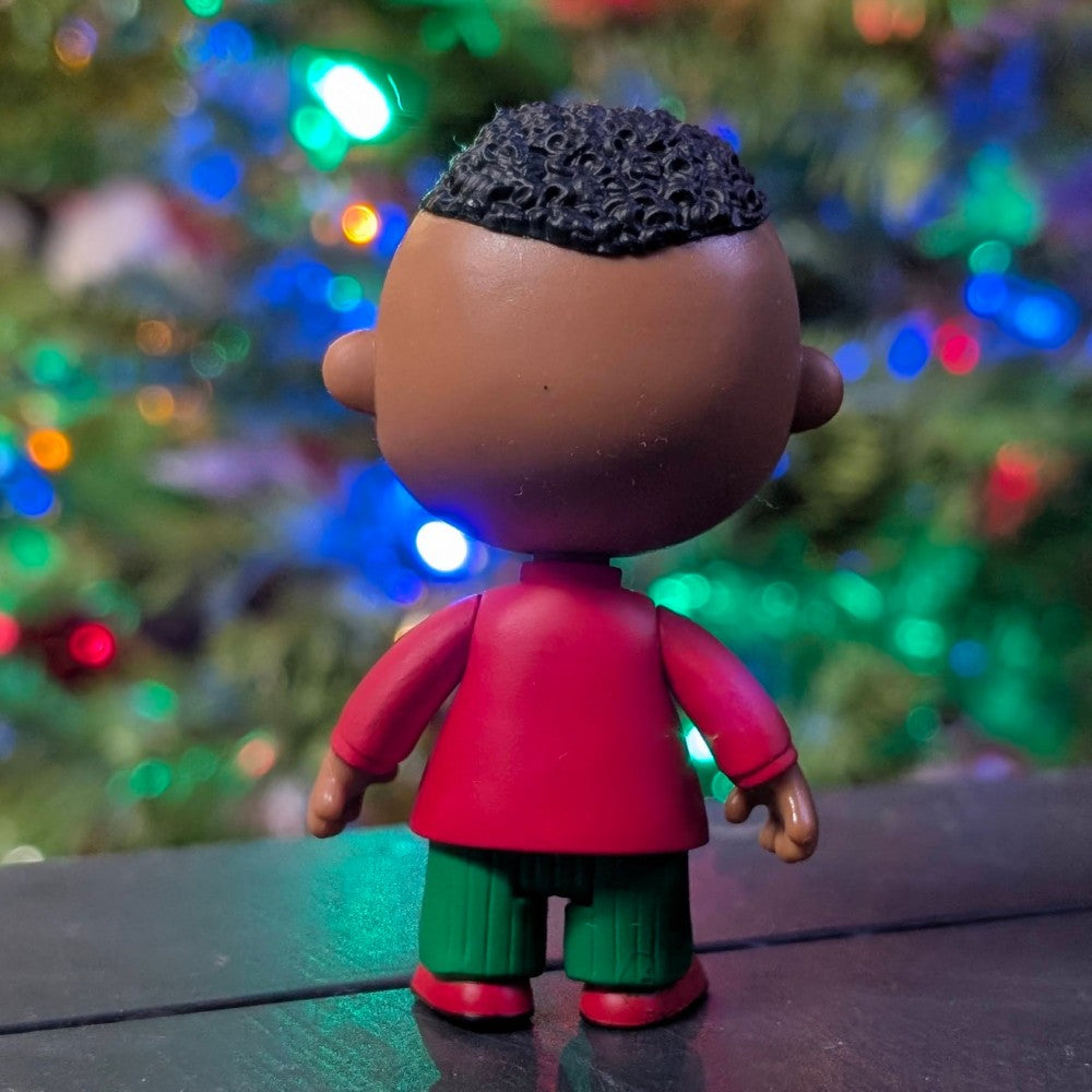 Loose Super7 Franklin Holiday ReAction figure facing away wearing red shirt and green pants with colorful holiday lights background