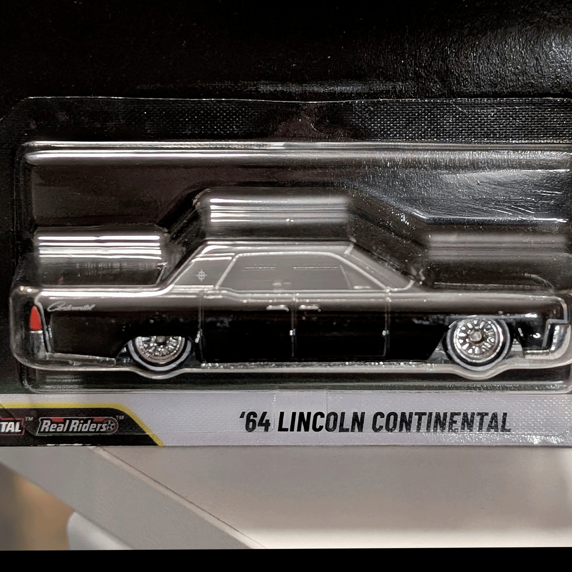 Mattel Hot Wheels ’64 Lincoln Continental die-cast model car in black with detailed wheels side view in packaging