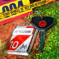 Doctor Collector Jurassic Park staff vehicle key with red dinosaur logo and R Muldoon identification tag on textured ground