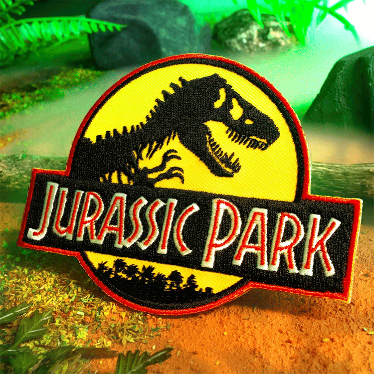 Doctor Collector Jurassic Park embroidered patch featuring classic dinosaur logo with yellow and red border on forest background