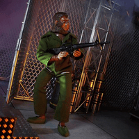 Mego 8-inch retro ape action figure in green military outfit holding rifle posed in industrial metal fence setting