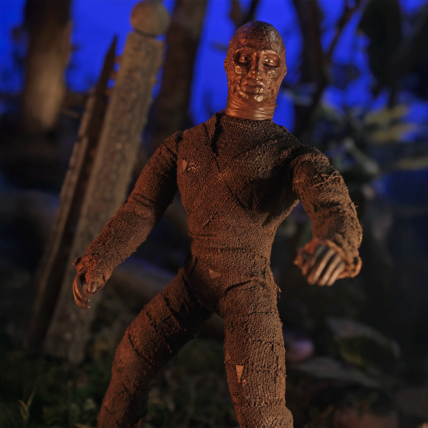 Mego 8-inch retro mummy figure wrapped in textured brown bandages posed in eerie, dark outdoor setting