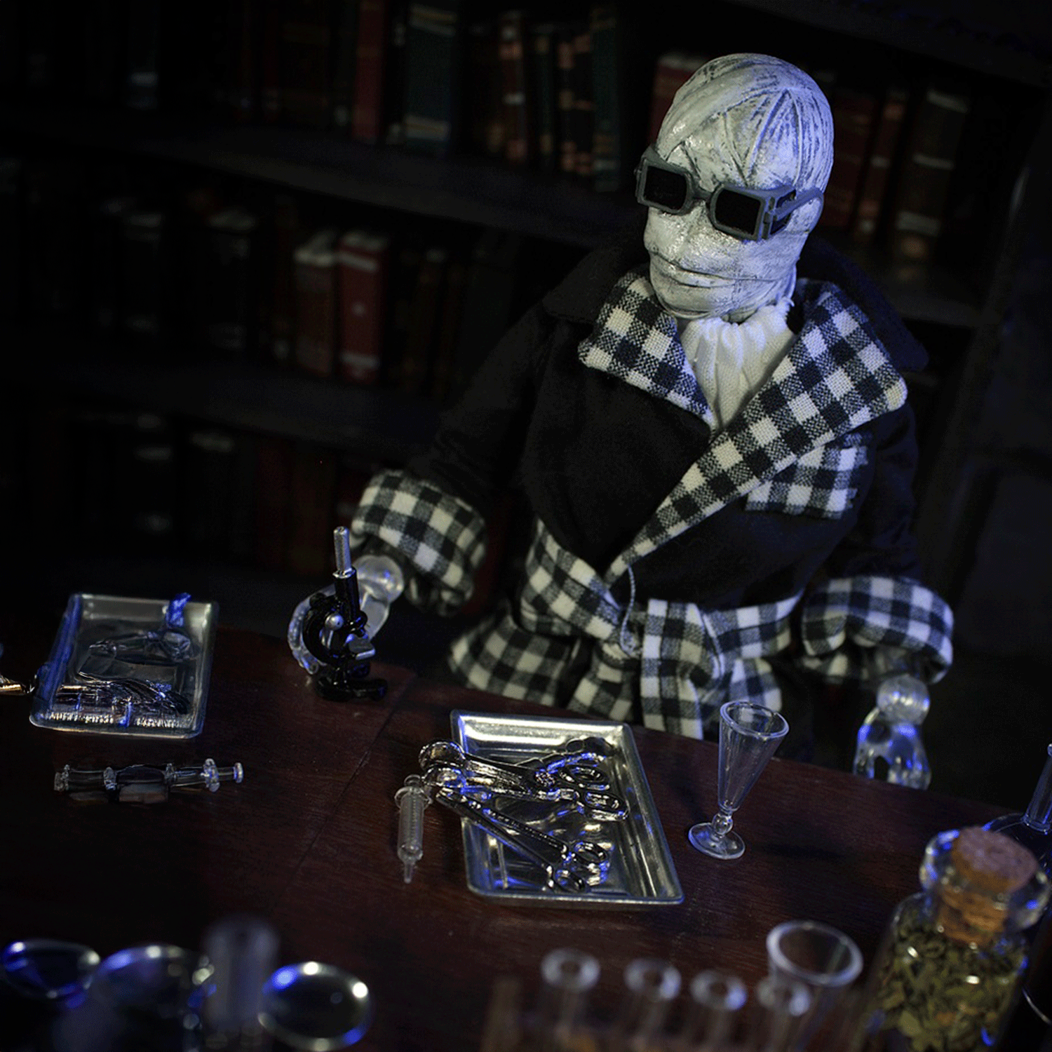 Mego 8-inch retro Invisible Man figure in checkered robe with black glasses and scientific tools on wooden table