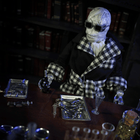 Mego 8-inch retro Invisible Man figure in checkered robe with black glasses and scientific tools on wooden table