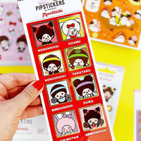 Hand holding PipSticks Monchhichi collection sheet with kawaii character portraits and gold foil accents on red border
