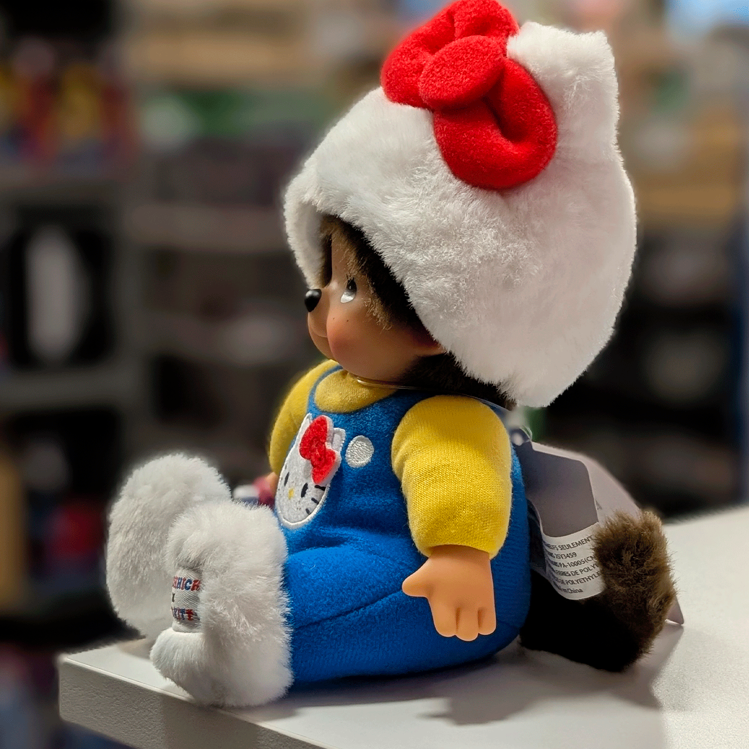 Sekiguchi Monchhichi 8-inch plush doll dressed as Hello Kitty in blue overalls and white cat hood sitting on surface