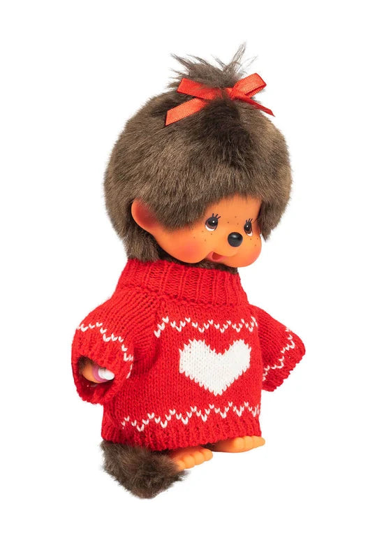 Monchhichi doll wearing a red heart sweater with a matching red hair bow