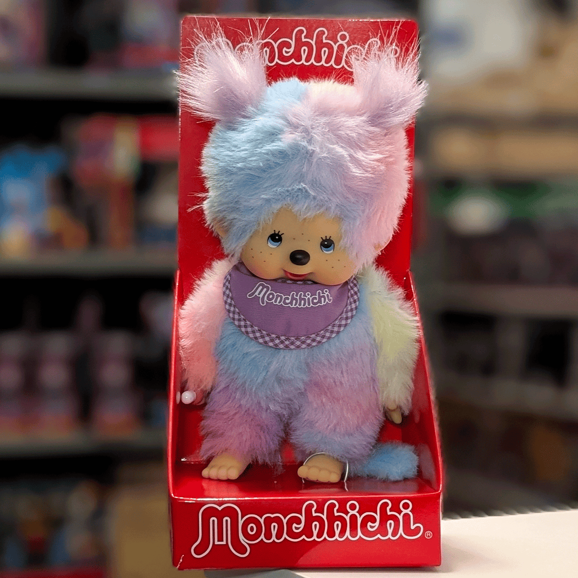 Sekiguchi 8-inch Monchhichi girl plush doll with multicolor pastel tie-dye fur and purple bib in red display box