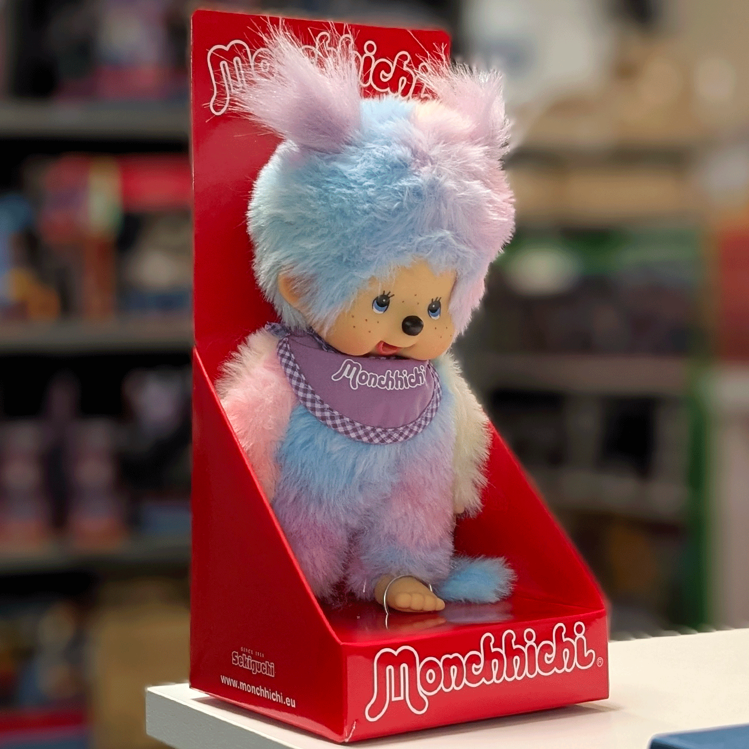 Sekiguchi 8-inch Monchhichi girl plush doll in pastel blue and pink tie-dye fur with purple bib in red display box