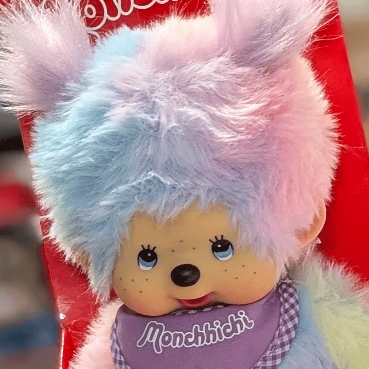 Sekiguchi 8-inch Monchhichi girl plush doll with pastel tie-dye fur and purple bib in red packaging