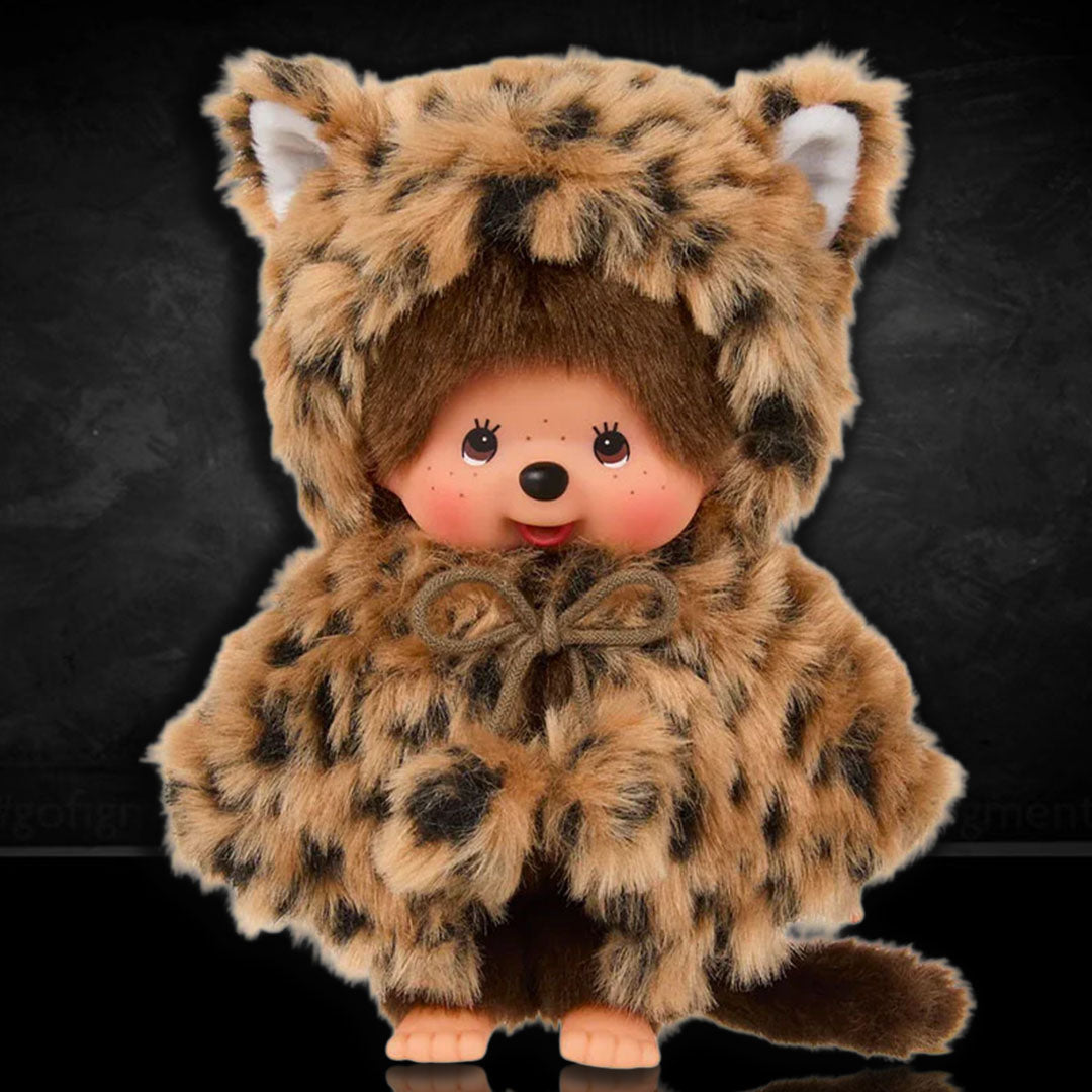 Sekiguchi Monchhichi plush monkey wearing a soft leopard hood and cape with cute ears and tail against black background