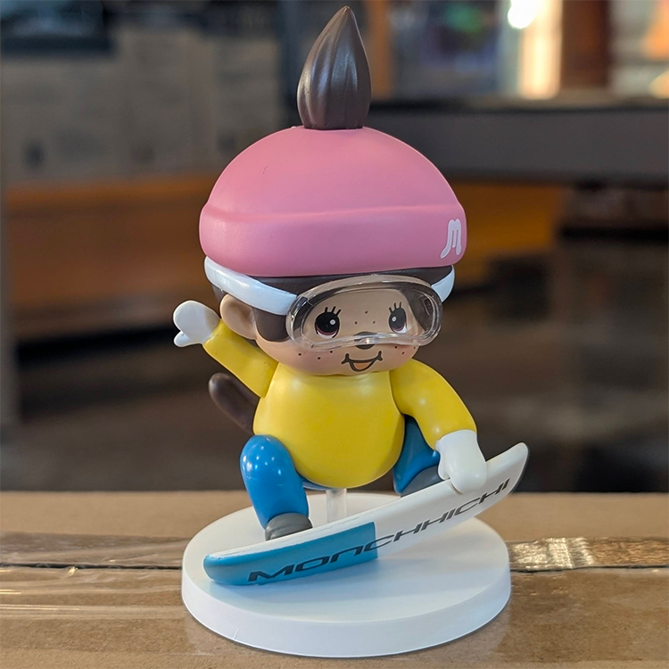 Sekiguchi Boy Monchhichi figure snowboarding with pink helmet goggles yellow shirt blue pants on snowy base