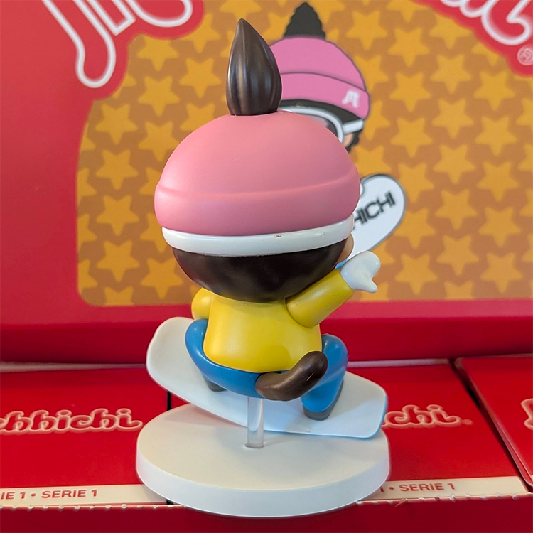 Sekiguchi Monchhichi Boy Snowboarding vinyl figure in yellow jacket and pink helmet on white snow display stand