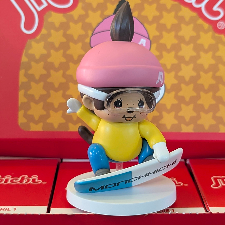 Sekiguchi Boy Monchhichi vinyl figure snowboarding with pink helmet and blue snowboard on white snow base