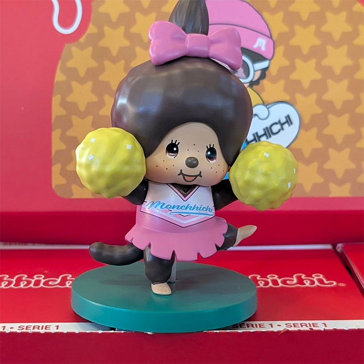 Sekiguchi Monchhichi girl cheerleader vinyl figure with pink outfit and yellow pom-poms on teal stand
