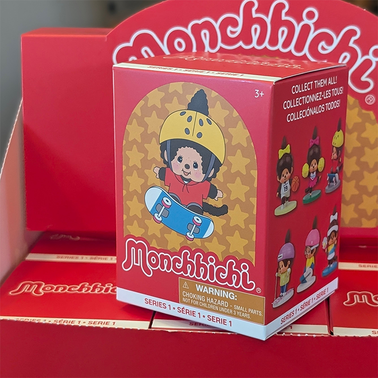 Sekiguchi Monchhichi Boy Snowboarding vinyl figure in yellow helmet and blue pants on red blind box with Monchhichi logo.
